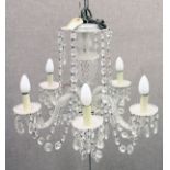 A VENETIAN STYLE CUT GLASS FIVE-BRANCH CHANDELIER, with scrolling arms and cut glass prism drops.