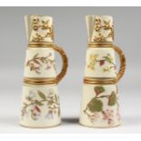 A PAIR OF ROYAL WORCESTER IVORY CLARET JUGS, gilded and painted with flowers on an ivory ground,