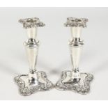 A SMALL PAIR OF SILVER CANDLESTICKS with shaped scrolled bases. 5.5ins high. Birmingham 1902.