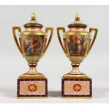 A GOOD PAIR OF 19TH CENTURY VIENNA TWO HANDLED URNS ON STANDS, with rich gilt decoration and