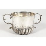 AN EARLY 18TH CENTURY TWO-HANDLED PORRINGER, semi fluted with scrolling handles, 3.5ins diameter.
