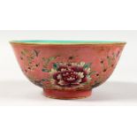 A CHINESE PORCELAIN BOWL, pink ground painted with flowers. 6.5ins diameter.