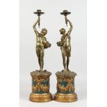 A PAIR OF 19TH CENTURY BRONZED CLASSICAL FIGURES, holding aloft candle sconces on plinths. 20ins