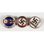 THREE CIRCULAR ENAMEL BADGES OF SWASTIKAS.