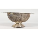 A DUTCH SILVER TWIN-HANDLED PEDESTAL BOWL/PORRINGER, with embossed and chased decoration. 9ins