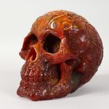 A LARGE AMBER STYLE MODEL OF A HUMAN SKULL. 7ins long.