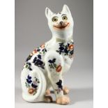 A GALLE PORCELAIN CAT, painted with flowers and glass eyes, (one leg repaired). 13ins high.