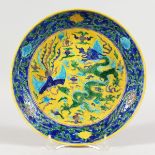 A CHINESE PORCELAIN PLATE, blue and yellow ground decorated with dragons. 8.75ins diameter.