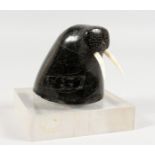 AN INUIT CARVED HARDSTONE GROUP OF A WALRUS HEAD, on a square onyx base. 3ins.