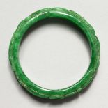 A CHINESE CARVED APPLE GREEN JADE BANGLE. 2.75ins diameter.