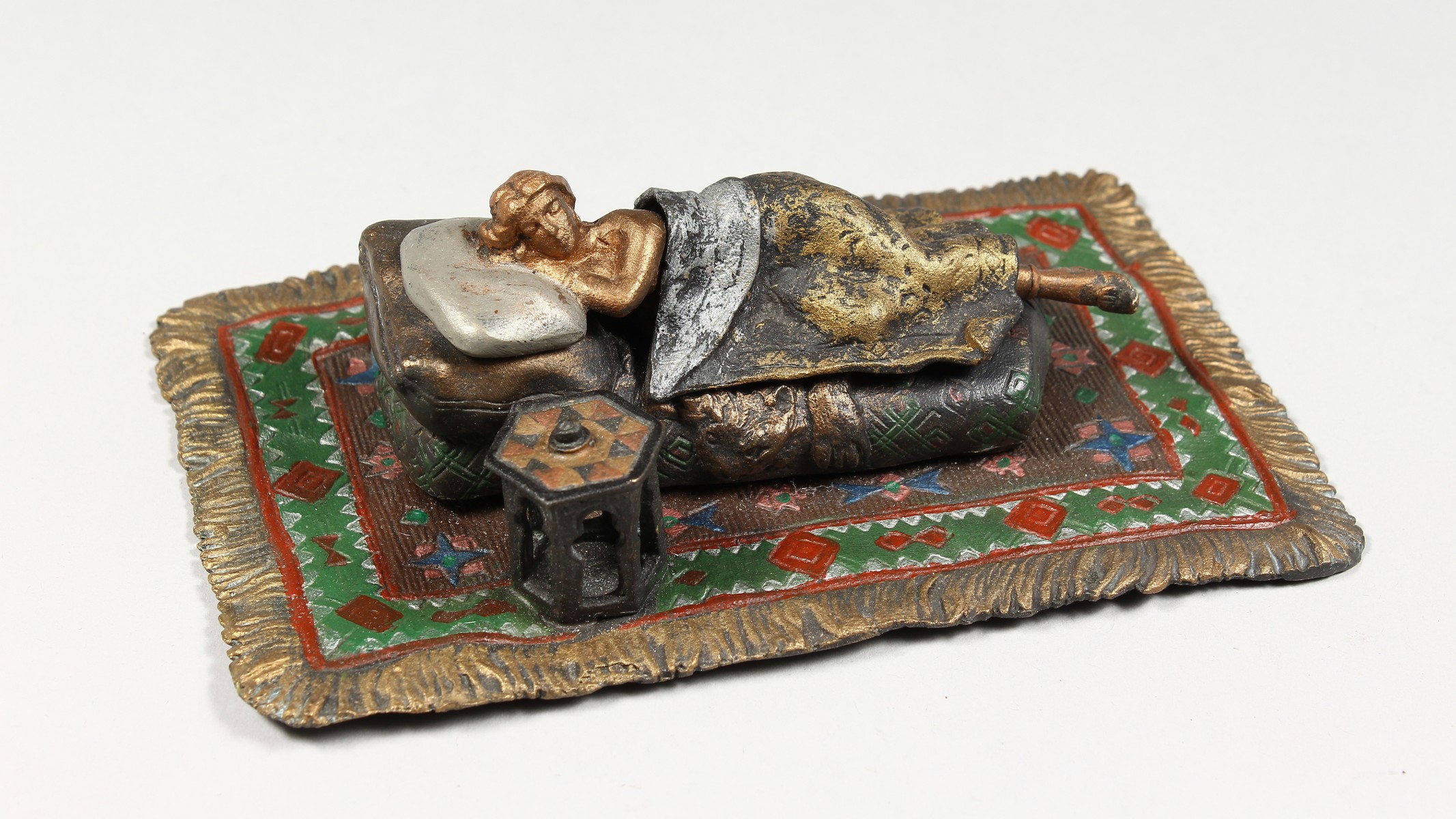 A VIENNA STYLE COLD PAINTED BRONZE MODEL OF A LADY SLEEPING ON A BED, on a Persian rug. 6.25ins