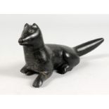 AN INUIT CARVED HARDSTONE GROUP OF A FOX LAYING DOWN. 9ins long.