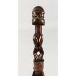 A NATIVE FLY WHISK, carved with two figures. 16ins long.