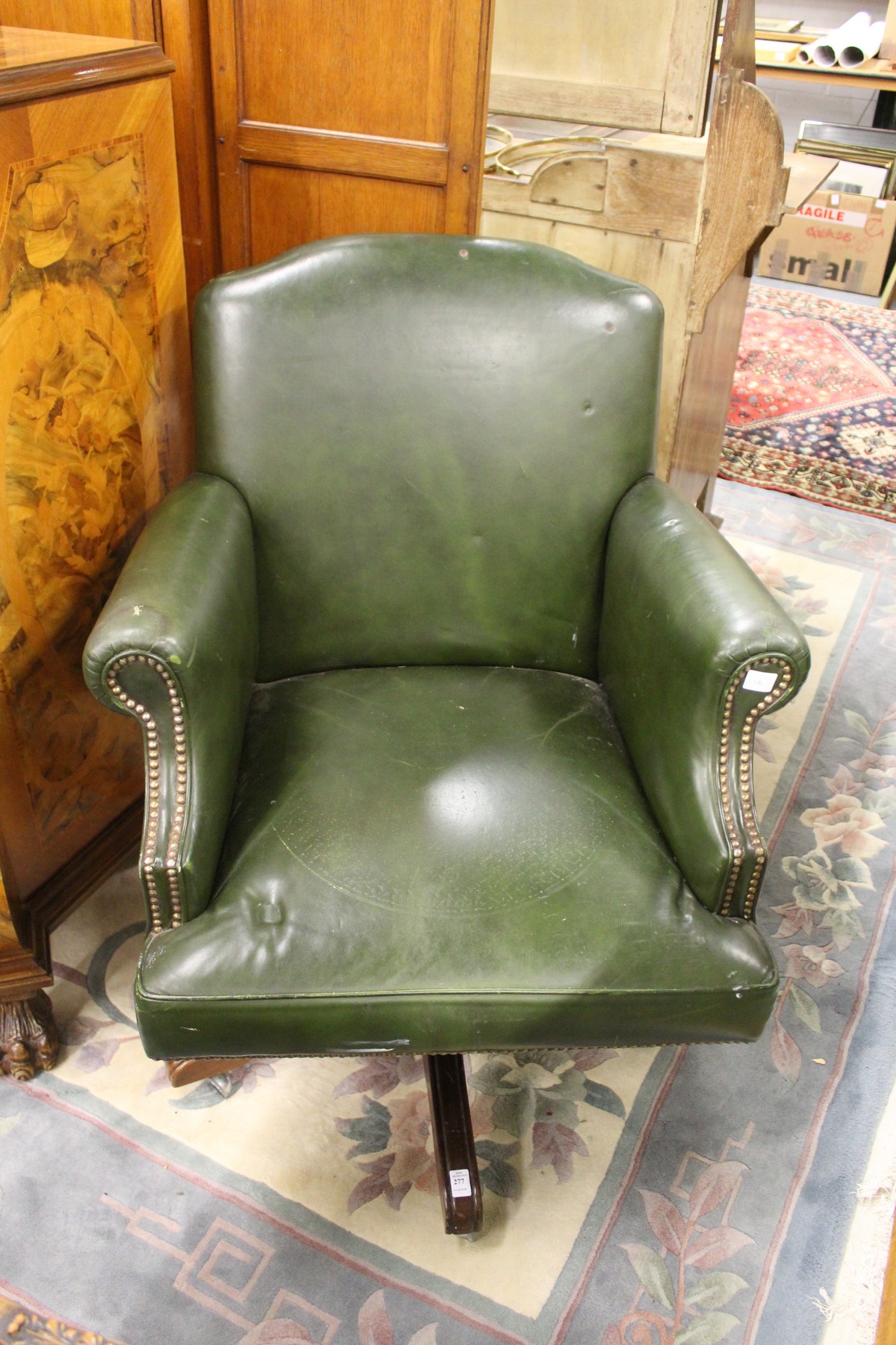 A green leather upholstered office swivel armchair.