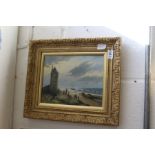 A small coastal landscape with figures and buildings, oil on board in a decorative gilt frame.