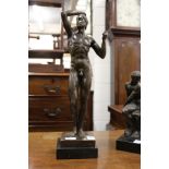 A bronze standing male nude on a square marble base.