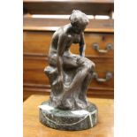 A cast bronze of a seated female nude on a circular marble base.