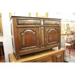 A 18th century oak small dresser base, with two drawers above two fielded panelled cupboard doors.