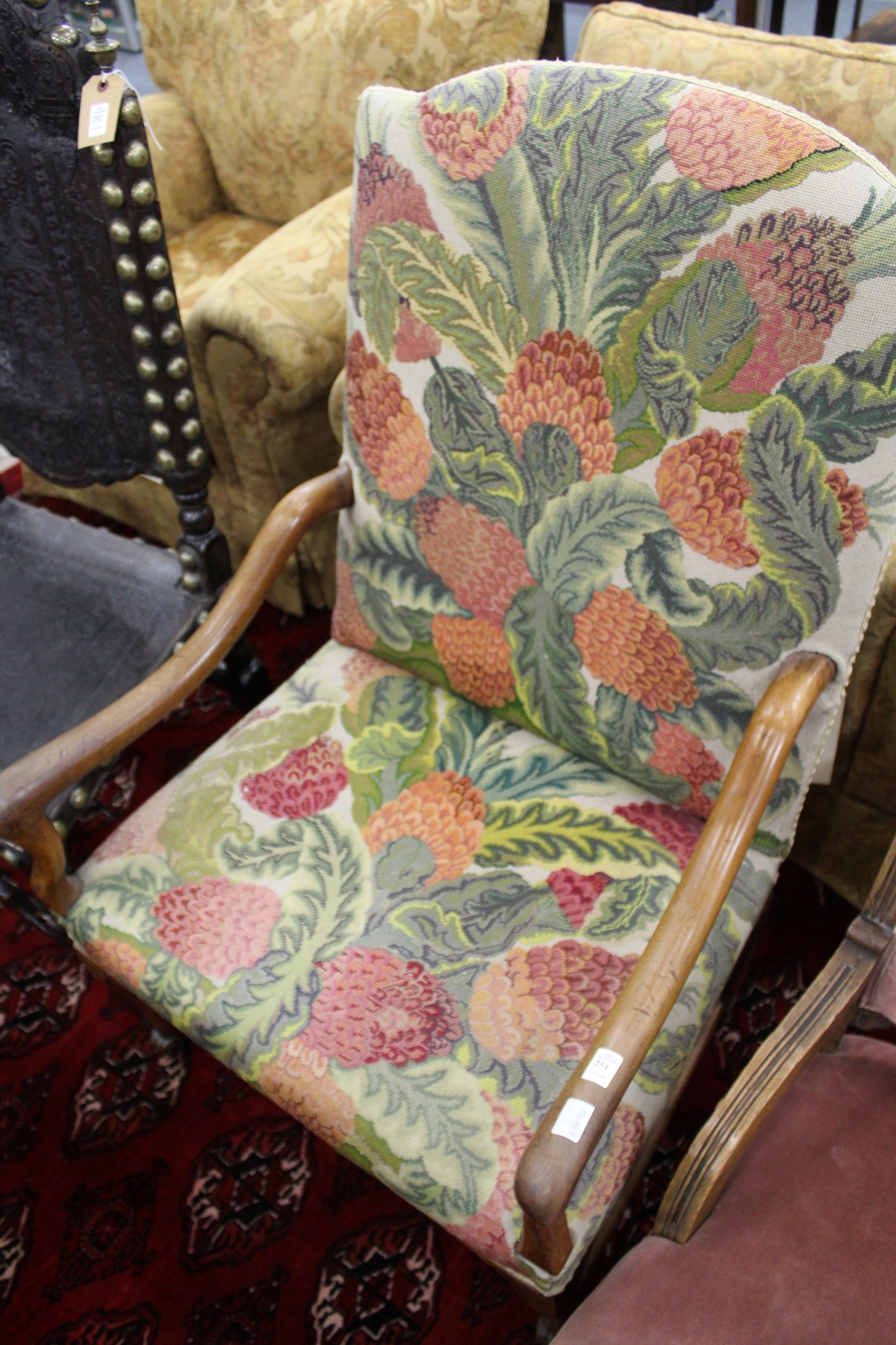 An 18th century continental walnut framed open armchair with needlework upholstered back and seat.