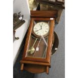 A modern wall clock and two copper pans.