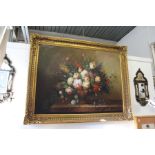 A still life of flowers in a vase on a ledge, oil on canvas, in a large decorative gilt frame.