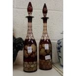 A pair of ruby coloured etched glass decanters (one neck repaired).