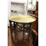 An eastern engraved brass tray top table with folding stand.