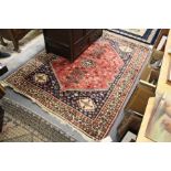 A Persian rug, red ground, the central panel with stylized tree and bird motifs.