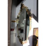 A decoratively framed oval wall mirror.