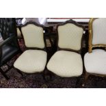 A pair of Victorian carved rosewood framed side chairs with upholstered backs and seats.