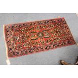 A small Persian rug, red ground with floral decoration.