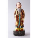 A CHINESE FAMILLE ROSE POTTERY FIGURE OF A SCHOLAR, holding a scroll upon a stylized base, 22cm