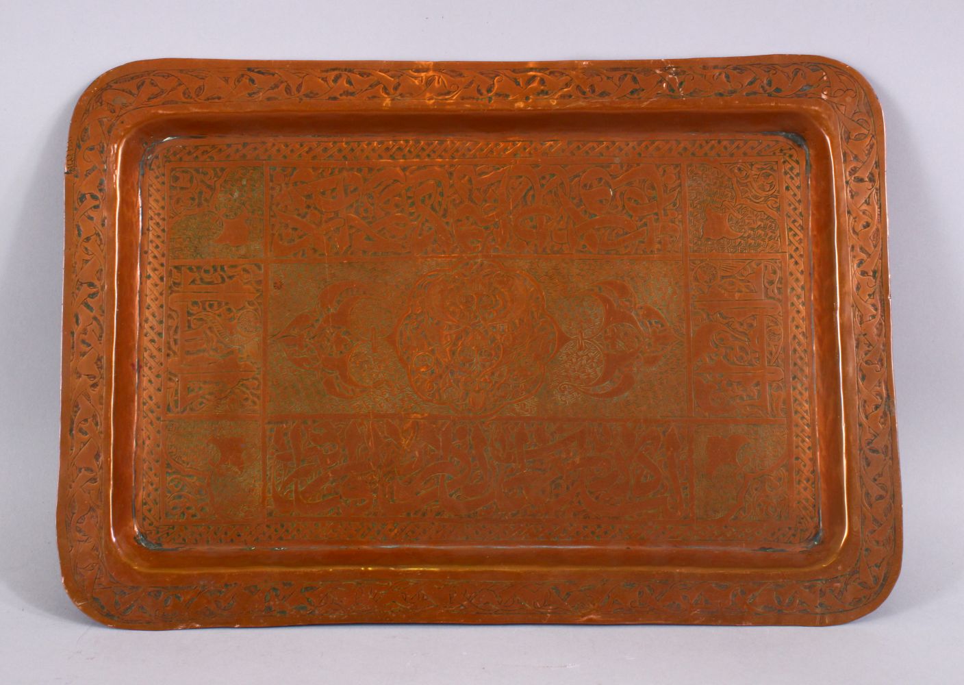 AN EARLY ISLAMIC CALLIGRAPHIC COPPER TRAY, the tray with formal floral motif and panels of