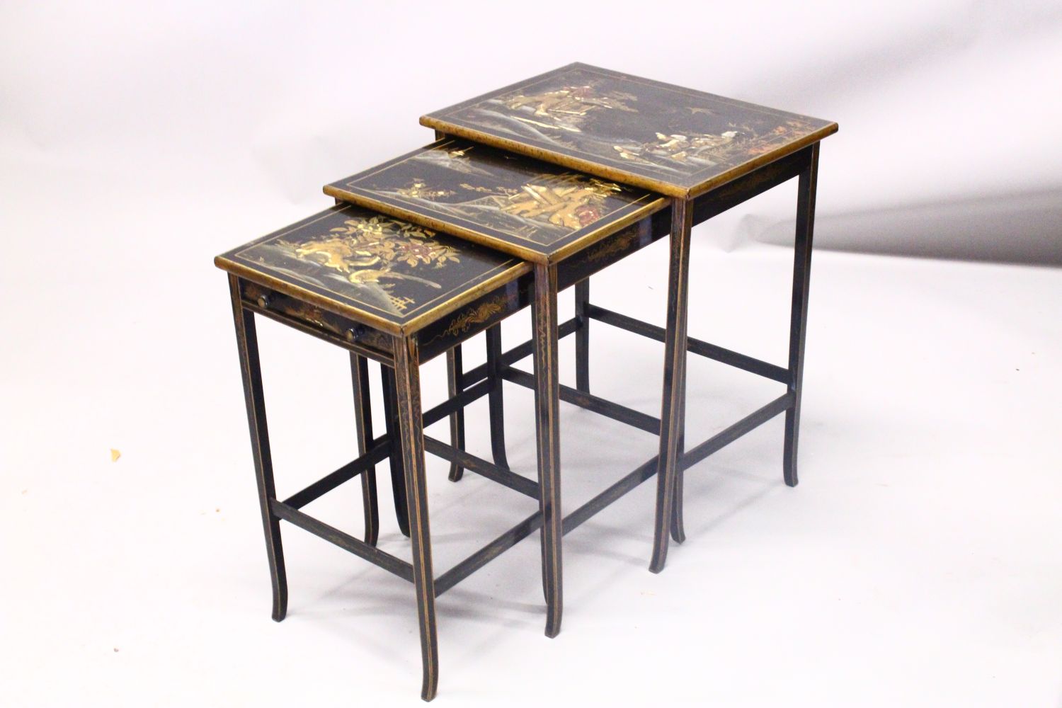 A 19TH CENTURY CHINESE LACQUER DECORATED NEST OF TABLES, decorated with views of landscapes and