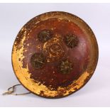 A 19TH CENTURY INDIAN PAINTED LEATHER SHIELD WITH BRASS BOSSES, with traces of gilding, 32cm.