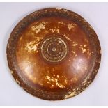 A 19TH CENTURY INDIAN LEATHER SHIELD, 34cm diameter.