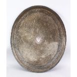 A LARGE INDIAN SILVERED BRONZE OR BRASS TRAY, with a central crest and scrolling foliate, 68.5cm x
