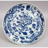 A 19TH / 20TH CENTURY CHINESE BLUE & WHITE PORCELAIN DRAGON DISH, with three five claw dragons,