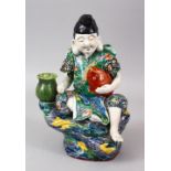 A GOOD JAPANESE MEIJI PERIOD KUTANI PORCELAIN FIGURE OF A GOD SEATED UPON A ROCK, holding his fish