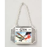 A SILVER PLATED DECANTER LABEL "GIN", enamel decorated with an aeronautical dog fight including "The