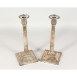 A PAIR OF ADAM DESIGN PLATE CANDLESTICKS with fluted stems, on shaped bases. 12ins high.