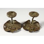 A SMALL PAIR OF BRONZE CANDLESTICKS, modelled as frogs on lily pads. 3ins wide.