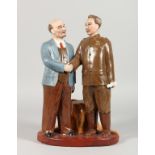 A RUSSIAN POTTERY GROUP, two figures standing shaking hands. 13.5ins high.