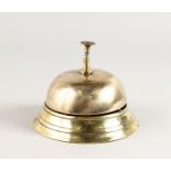 A CIRCULAR BRASS DESK BELL. 5.5ins diameter.