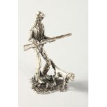 A MINIATURE SILVER FIGURE OF A MAN with a gun and a dog.