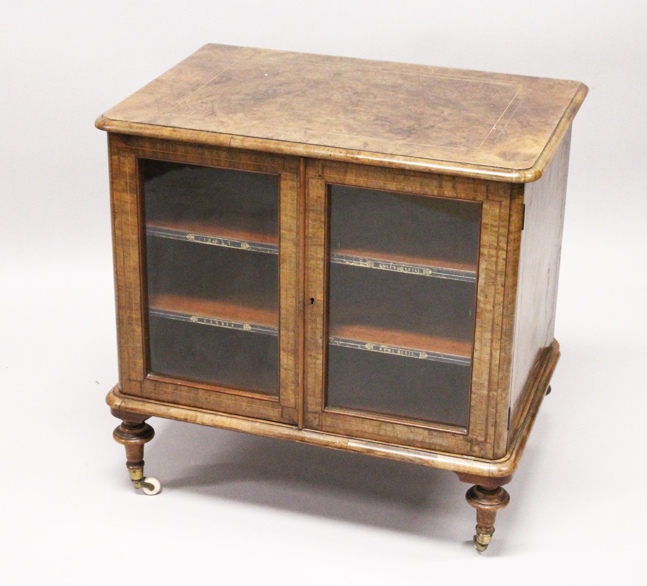 A VICTORIAN WALNUT LOW TWO DOOR MUSIC CABINET, with two shelves, on turned feet. 2ft 3ins wide x 2ft