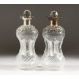 A PAIR OF HOURGLASS DECANTERS, with embossed silver rims and collars, London 1900. 8.5ins high.