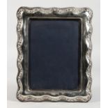 A SILVER PHOTOGRAPH FRAME with shaped edge. 11ins x 8ins.