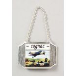 A SILVER PLATED DECANTER LABEL "COGNAC" enamel decorated with a Spitfire.