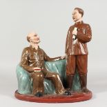 A RUSSIAN POTTERY GROUP, two figures, one seated. 13.5ins high.